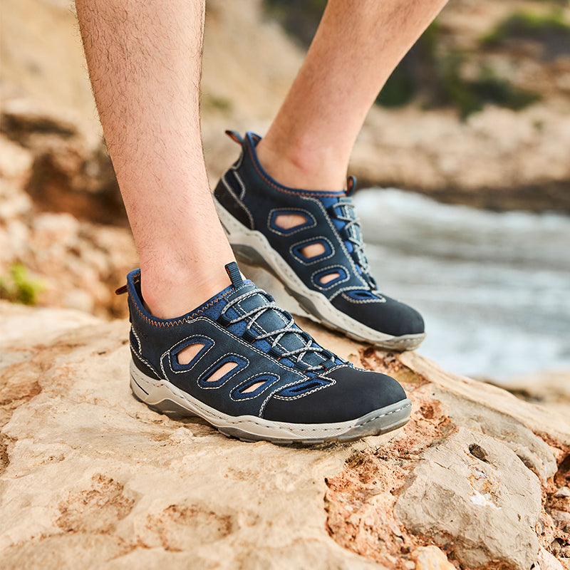 Men's blue lace-up sandals on rocky path, breathable cutout design