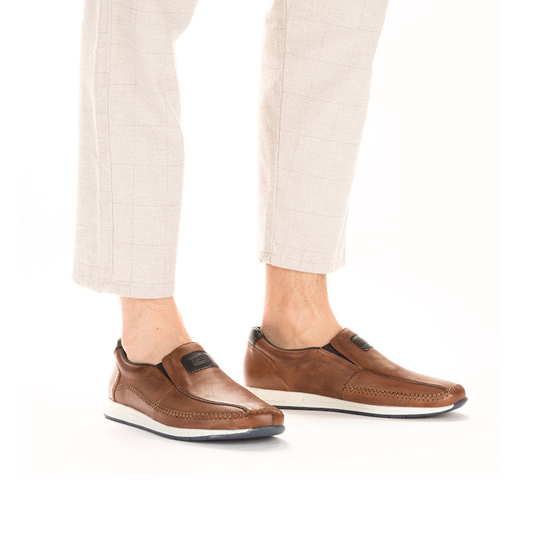 Men's brown leather slip-on loafers worn with light trousers and cushioned collars