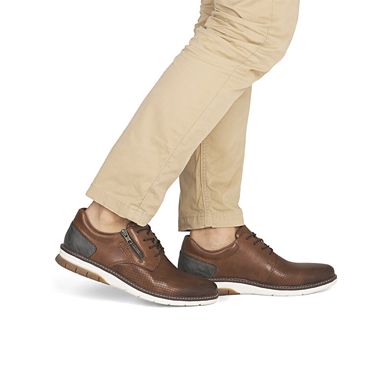 Brown leather men's business shoe with side zip and lace-up, worn with trousers
