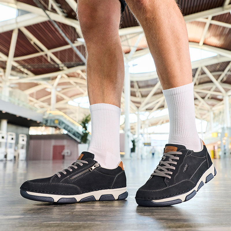 Men's lace-up sneakers on feet, dark blue upper and chunky contrast outsole