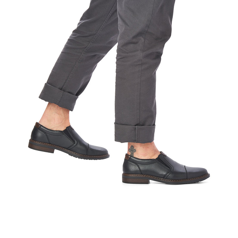 Men's black leather slip-on shoes with dark trousers cuffs