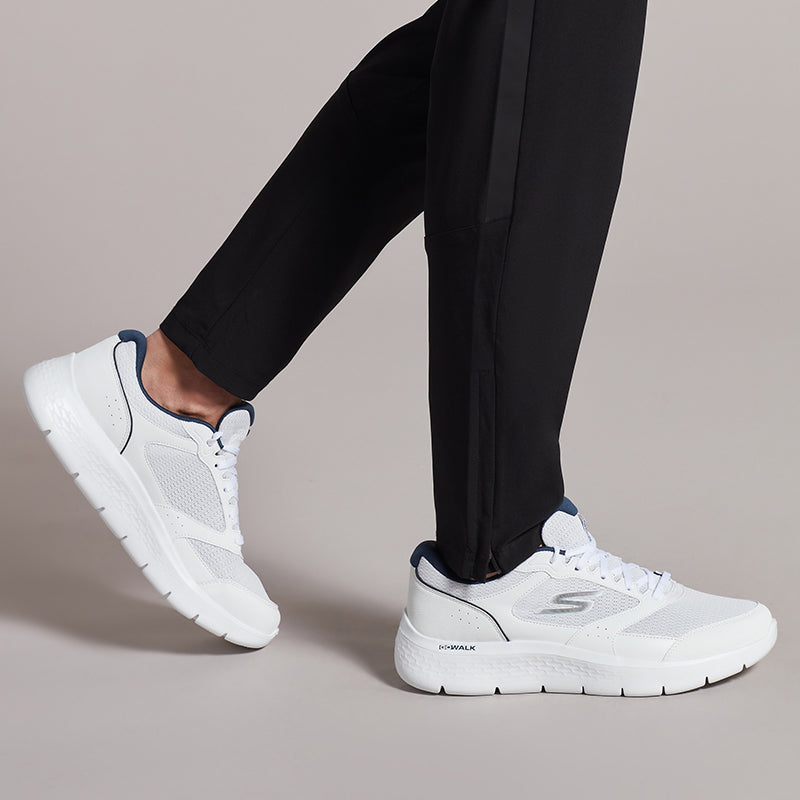 Men's white Skechers sneakers on feet, lace-up with navy heel trim and sole