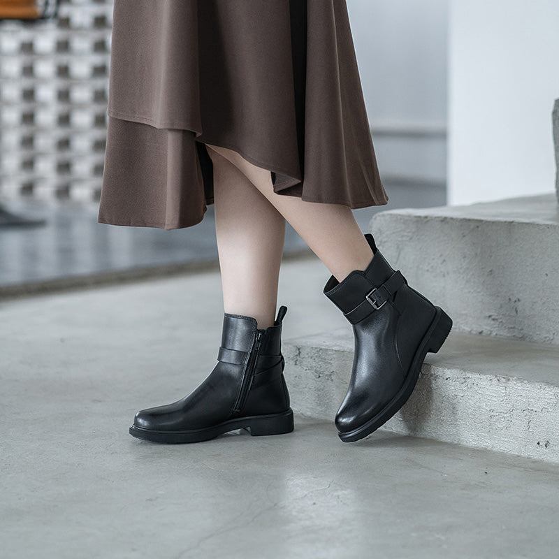Black leather womens ankle boots with buckle strap, worn with a midi dress
