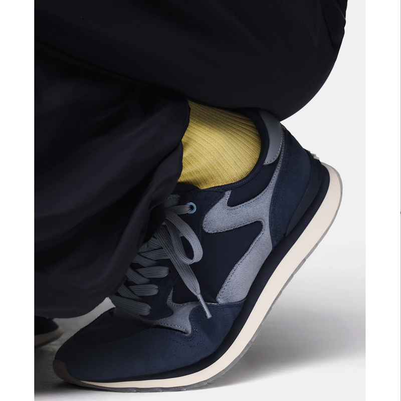 Men's blue leather sneaker close-up with gray laces and cushioned collar
