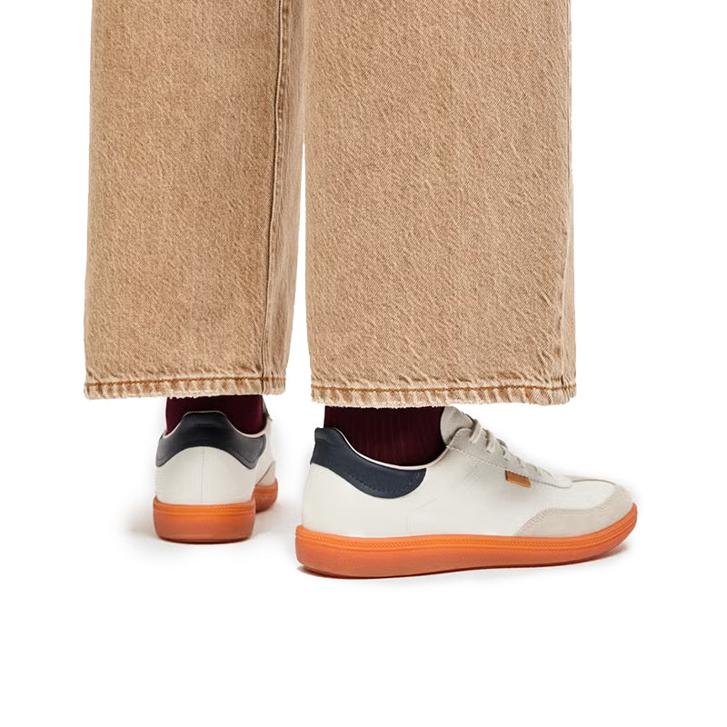 Low-top sneakers, white uppers with navy heel, orange outsole; rear view
