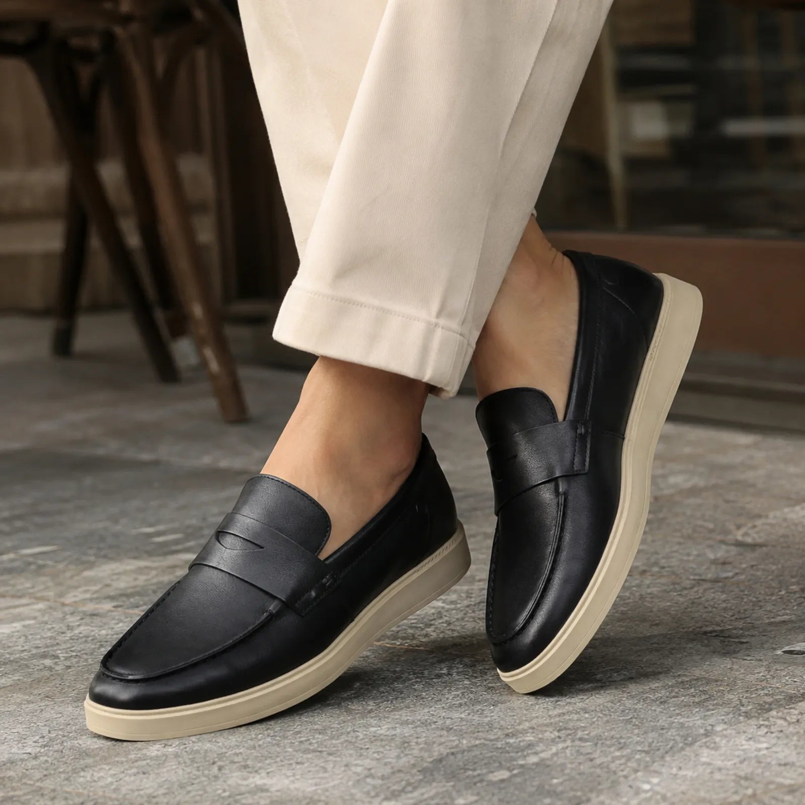 Men's black leather penny loafers on feet with light tan cushioned platform sole