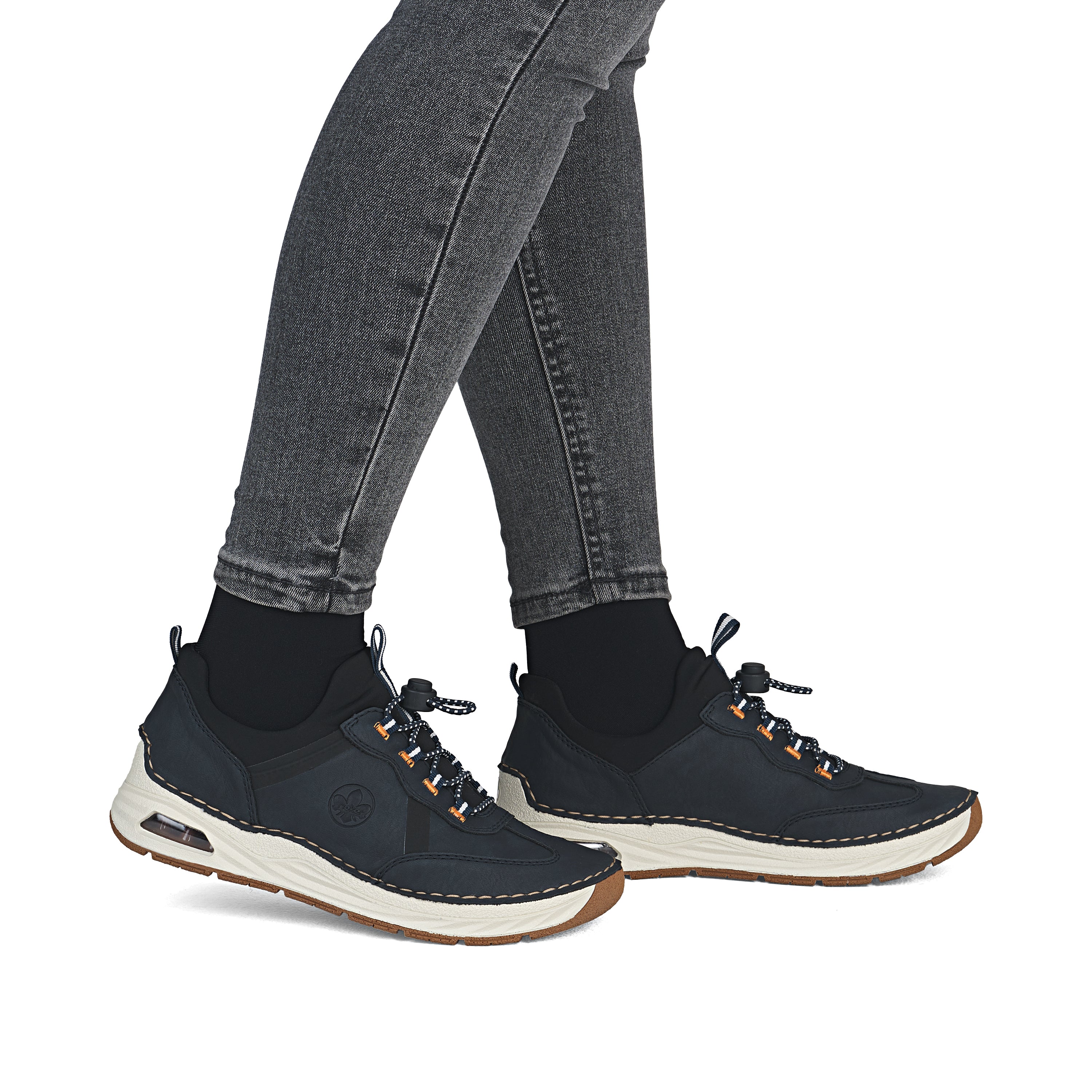 Navy lace-up sneakers worn with dark jeans and white outsole