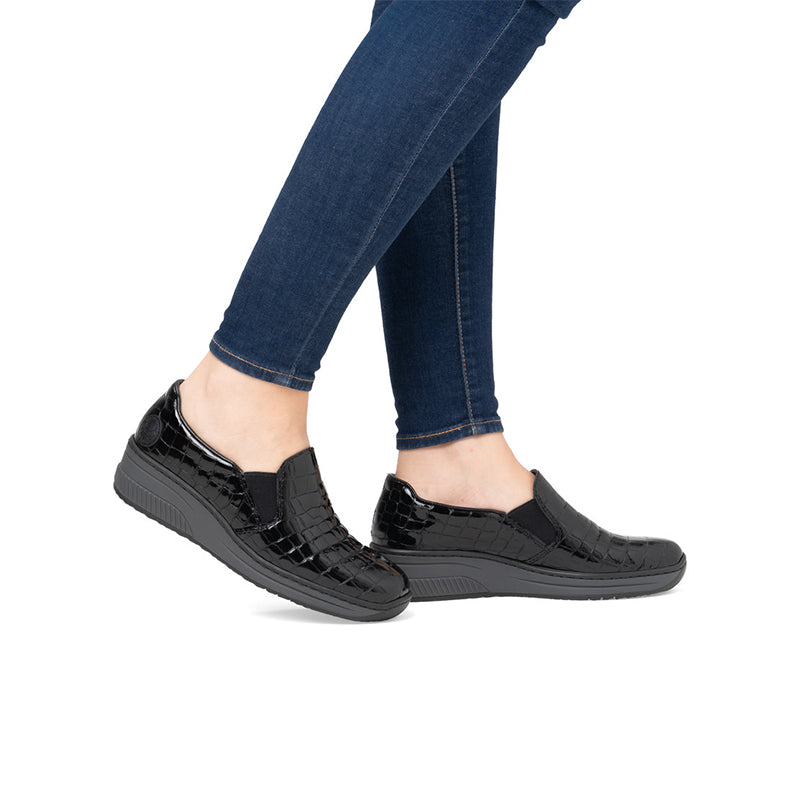 Rieker womens loafers on model, black glossy slip-on with wedge sole and jeans