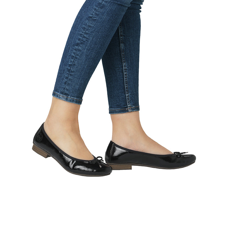 Black ballerina flats with bow front, worn with cuffed blue jeans