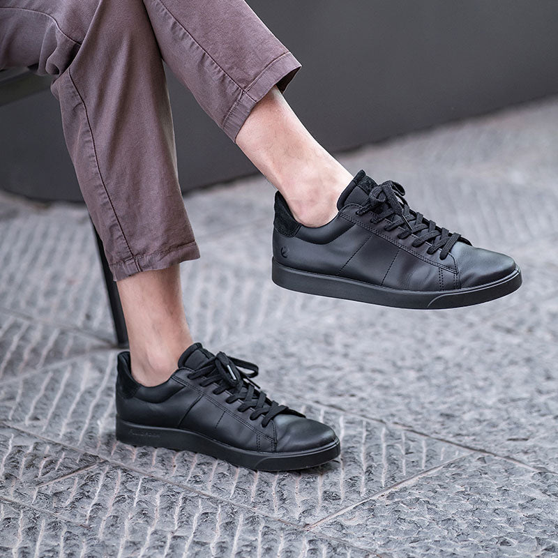 Men's leather sneakers, black, shown on feet with ankle-length pants