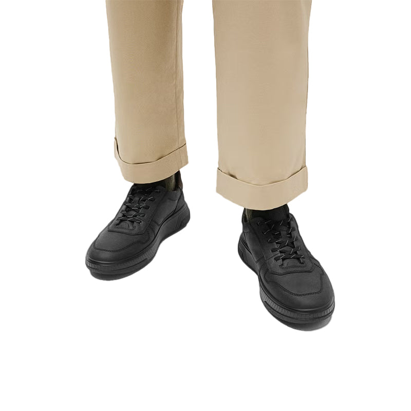 Men's black lace-up sneakers worn with beige pants, standing view