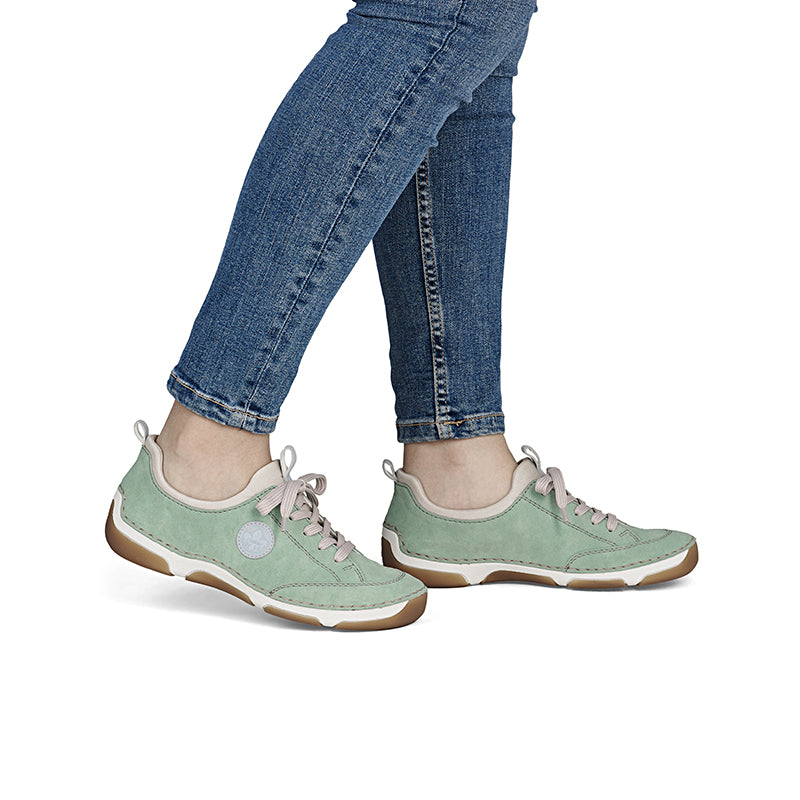 Green lace-up loafers with white sole, shown on feet with jeans