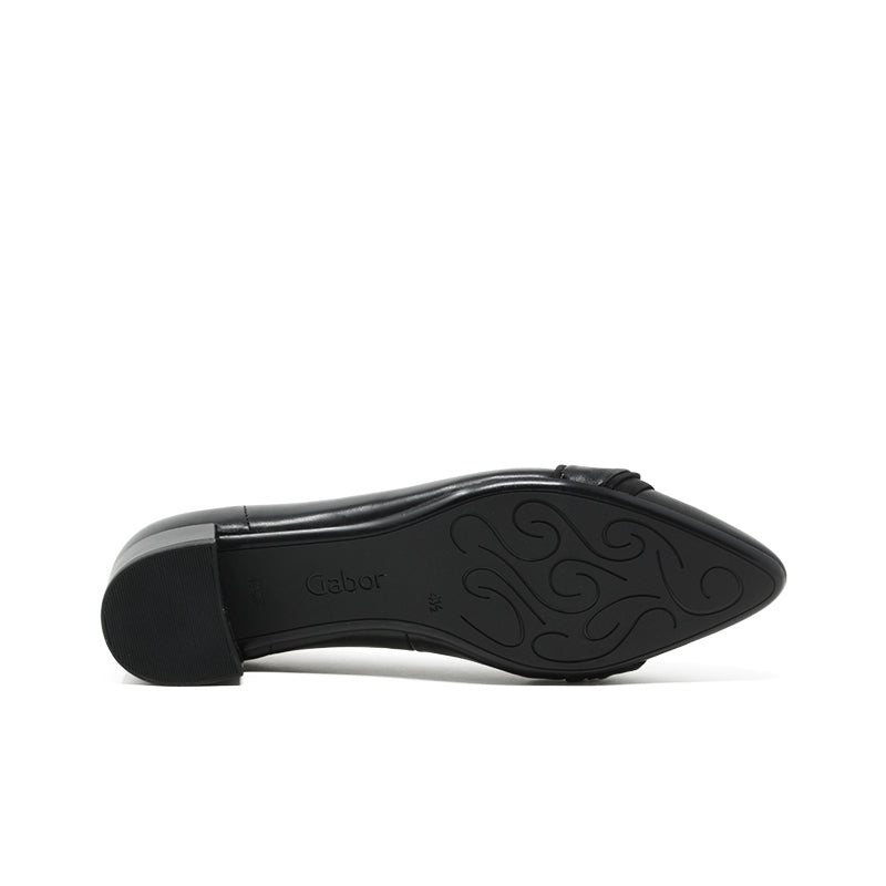 Women's black leather pumps outsole view with patterned tread and low block heel
