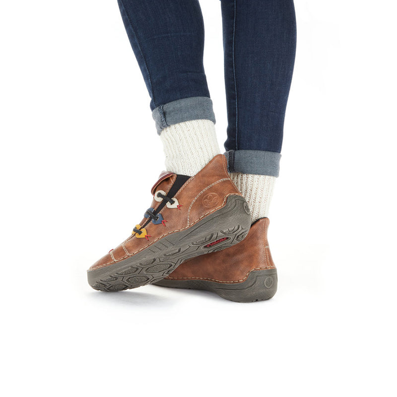 Brown sneaker on foot with textured outsole and laces