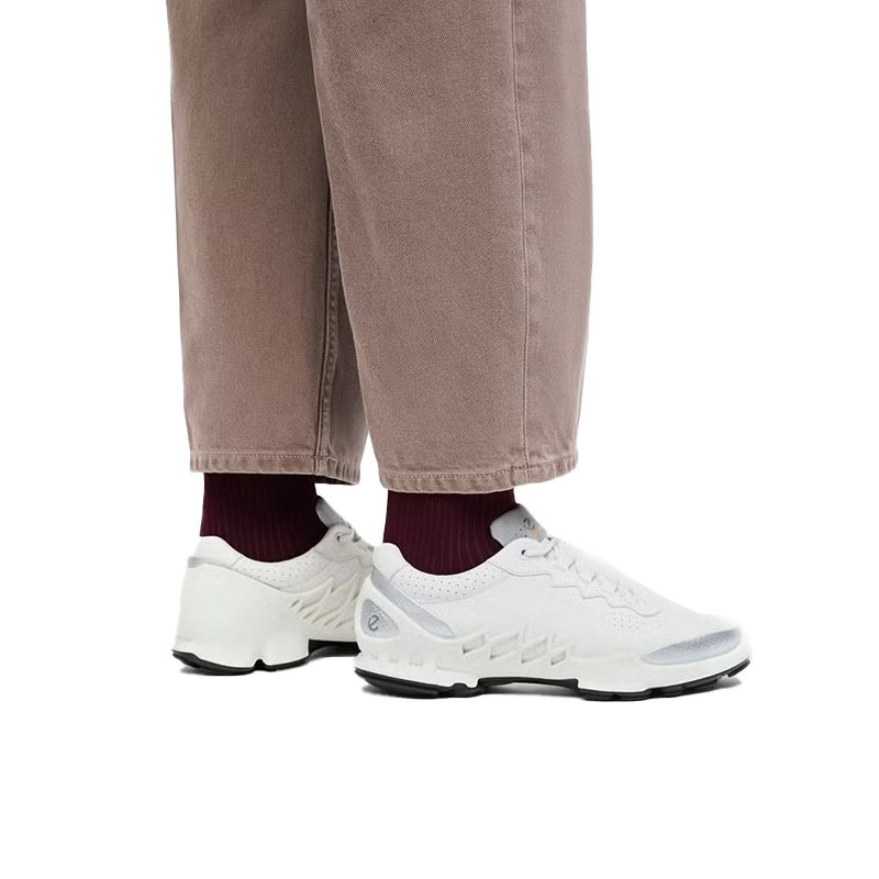 White leather sneakers worn with maroon socks and taupe pants, side angle
