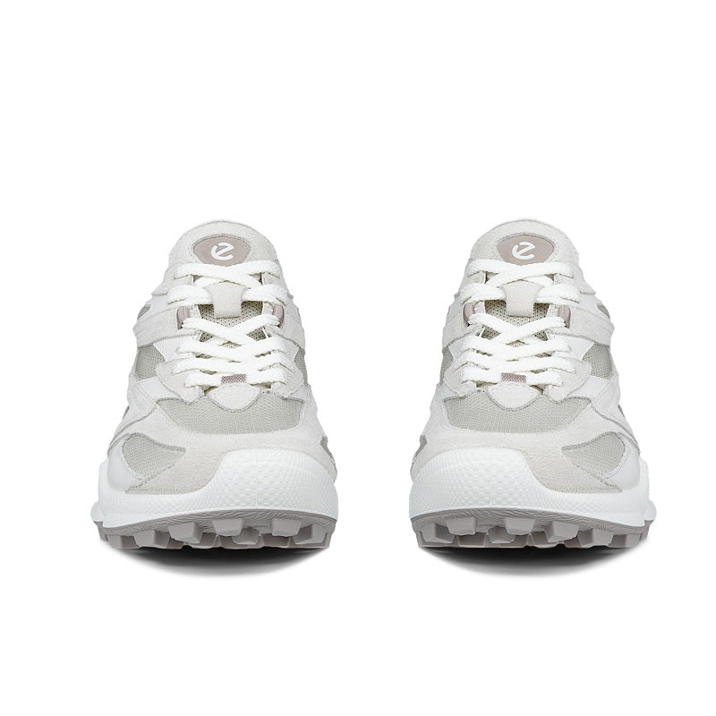 Pair of white women’s trail sneakers with lace-up design and thick treaded outsole