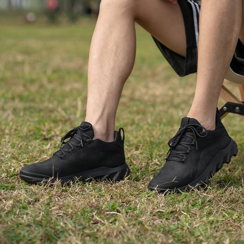 Pair of black lace-up outdoor trainers standing on grass with thick tread