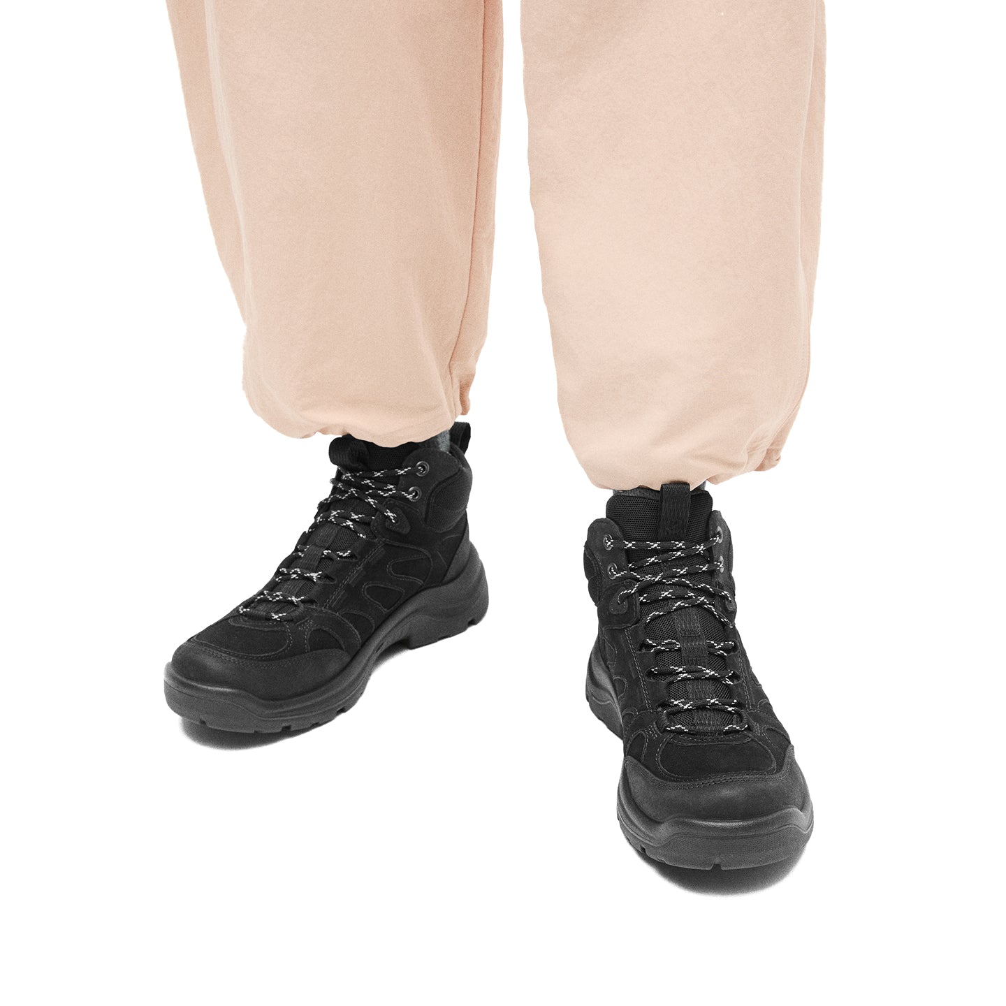 Women’s black lace-up boots on feet with light pants