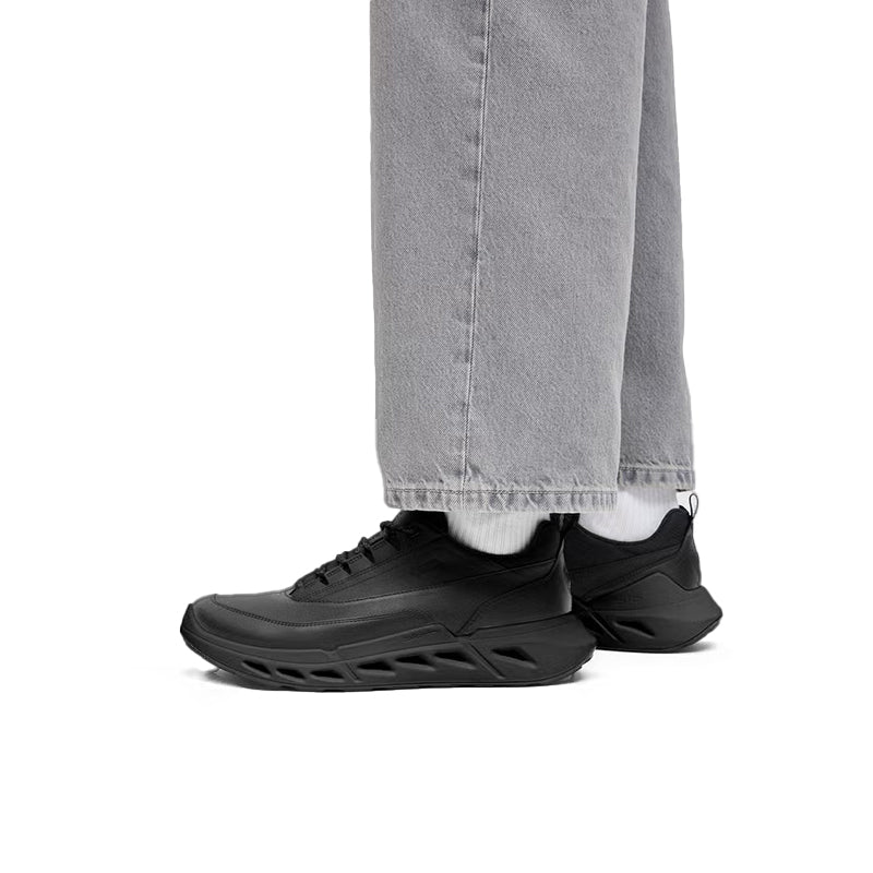 Black lace-up sneakers shown with light gray pant cuffs