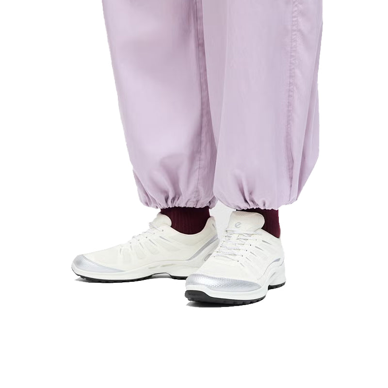 White lace-up sneakers worn with light purple joggers