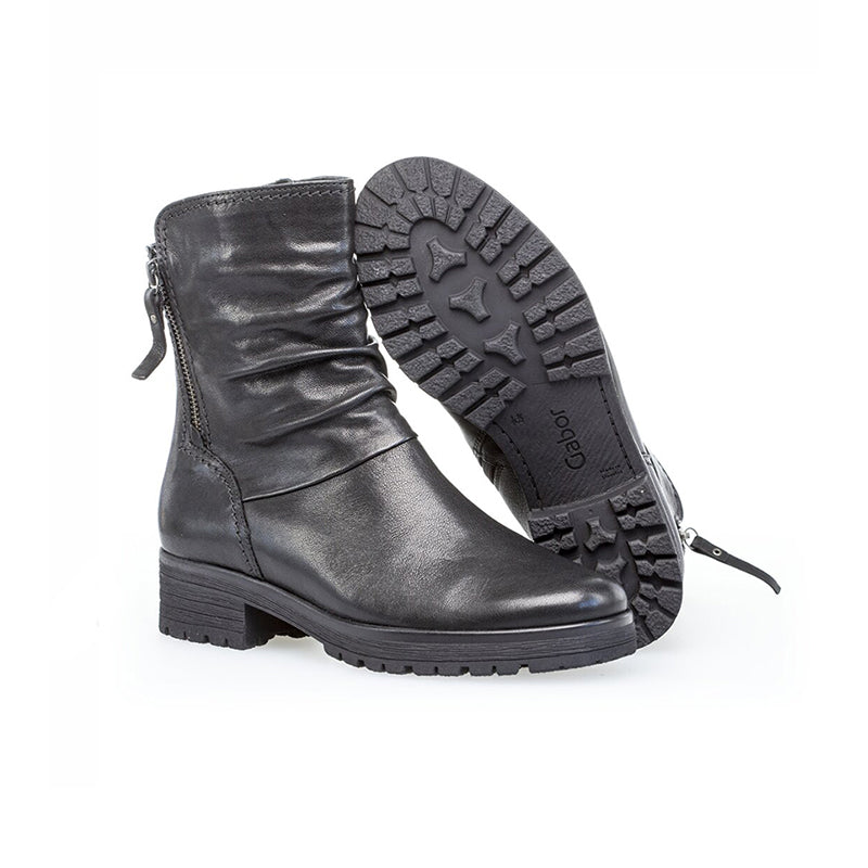 Black leather ankle boots shown with outsole view and side zip, lug tread sole