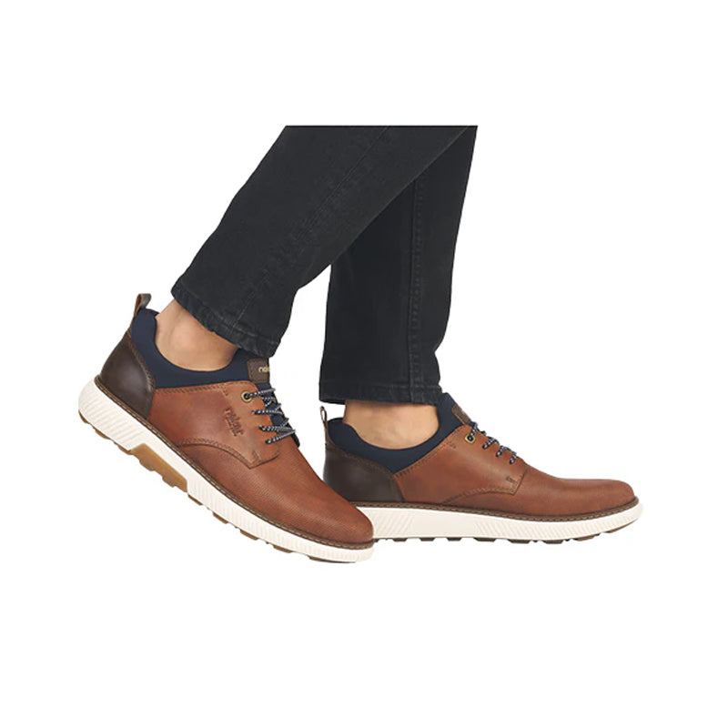 Men's brown sneakers with dark blue accents and white rubber sole, worn with pants