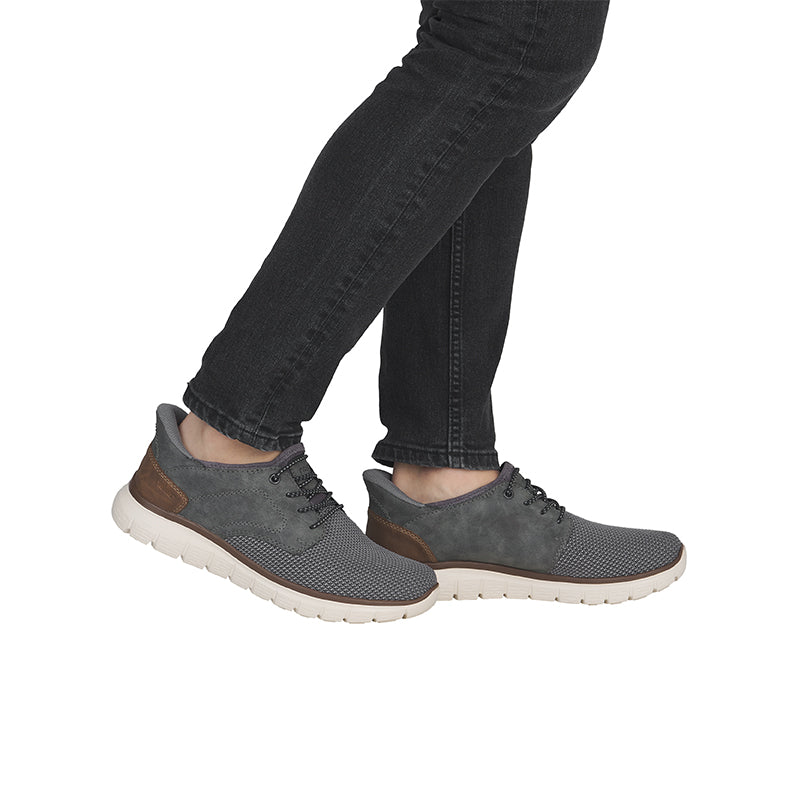 Men’s lace-up casual shoes on feet, dark grey knit and suede uppers with white sole