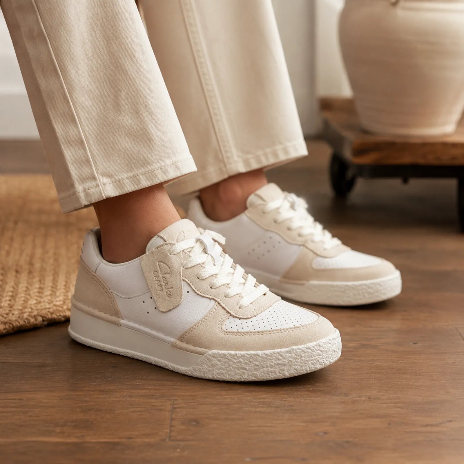 Women’s white sneakers with tan heel panel and lace-up, worn with light pants