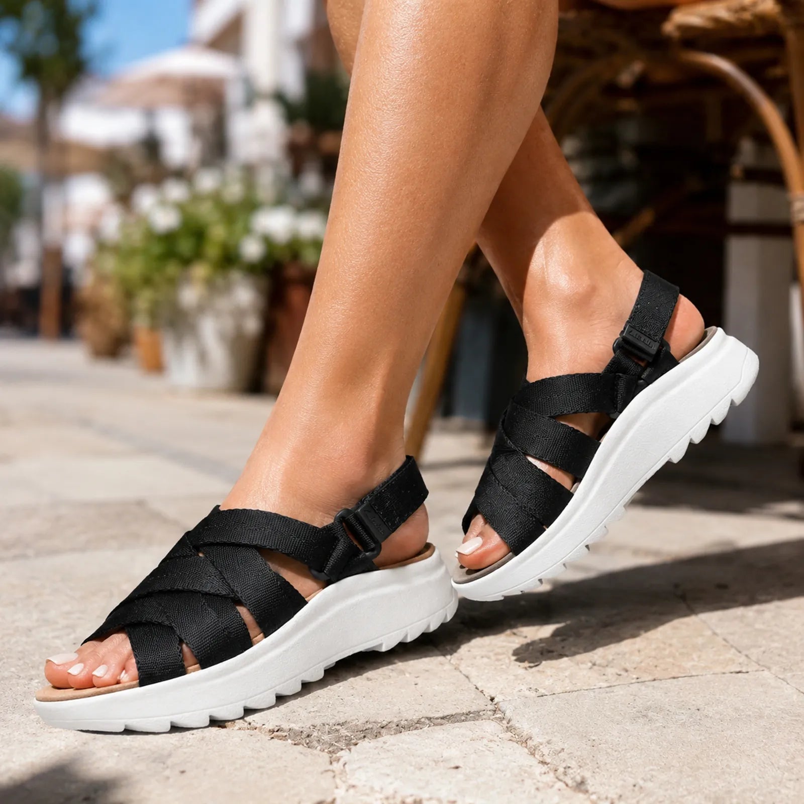 Close-up of women’s black sandals with hook-and-loop strap and thick white sole