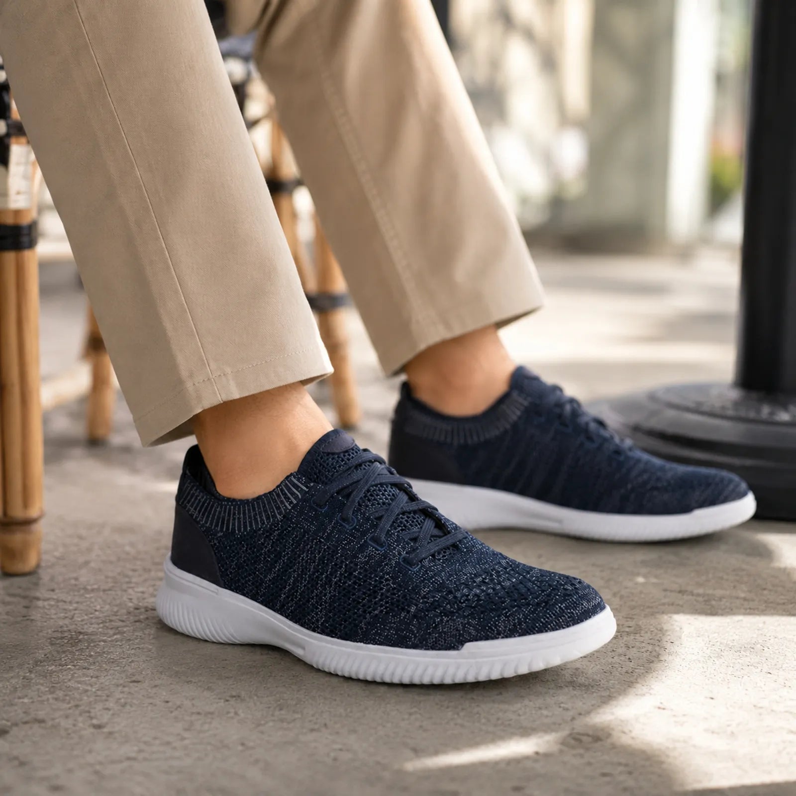Dark knit lace-up sneakers with white sole visible under pant hem