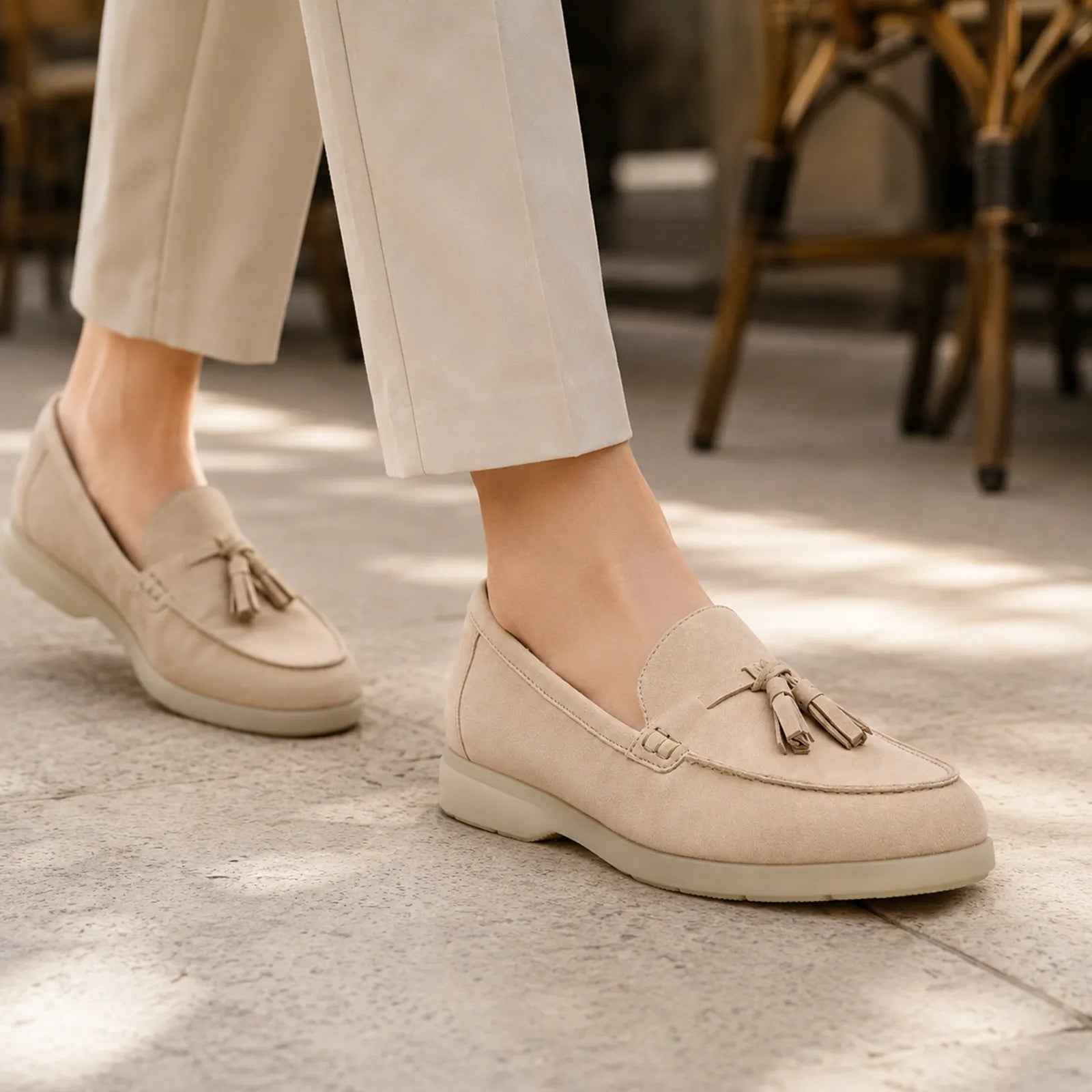Women's light pink suede loafers with tassel detail, worn with cropped trousers