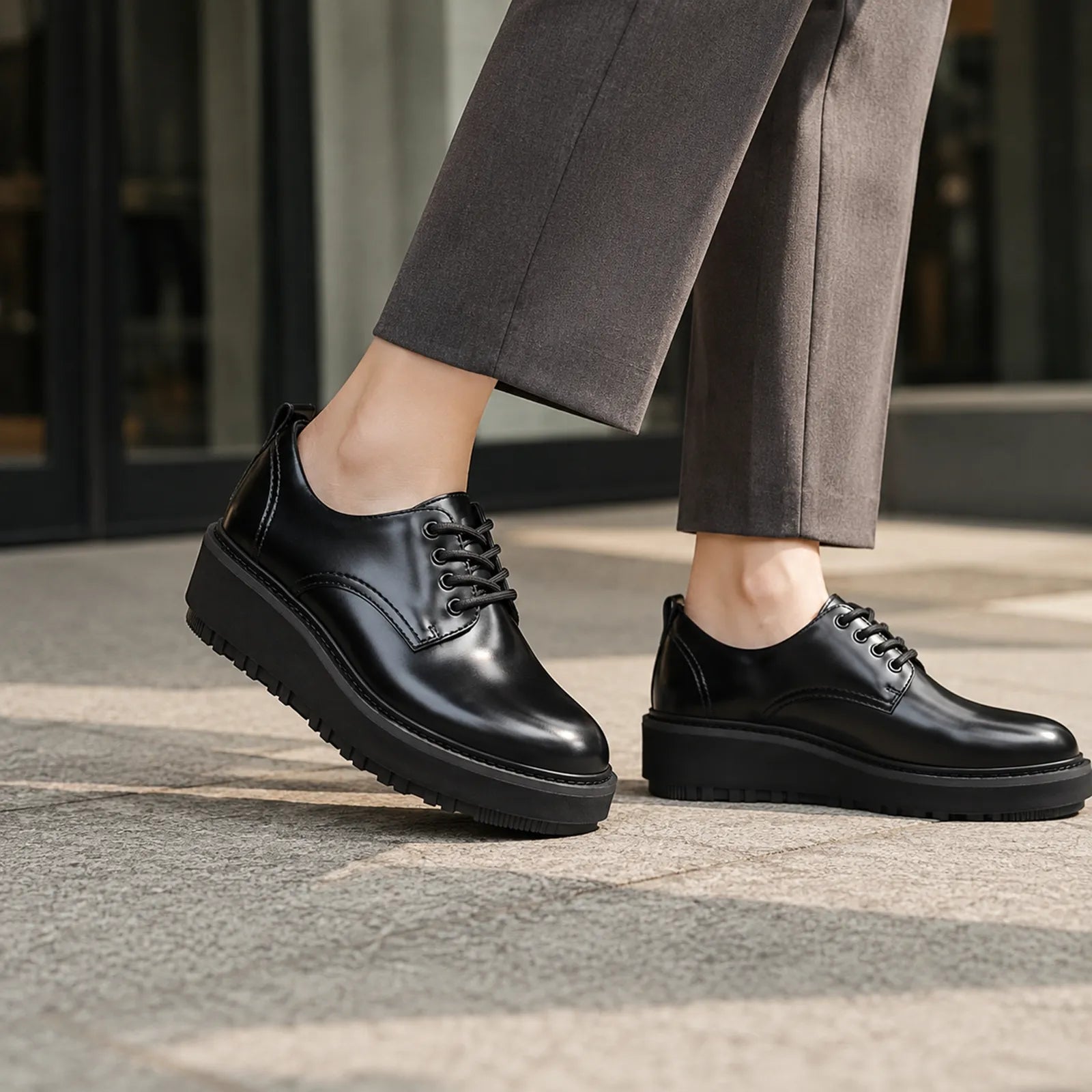 Black leather lace-up derby shoes with chunky sole on outdoor pavement