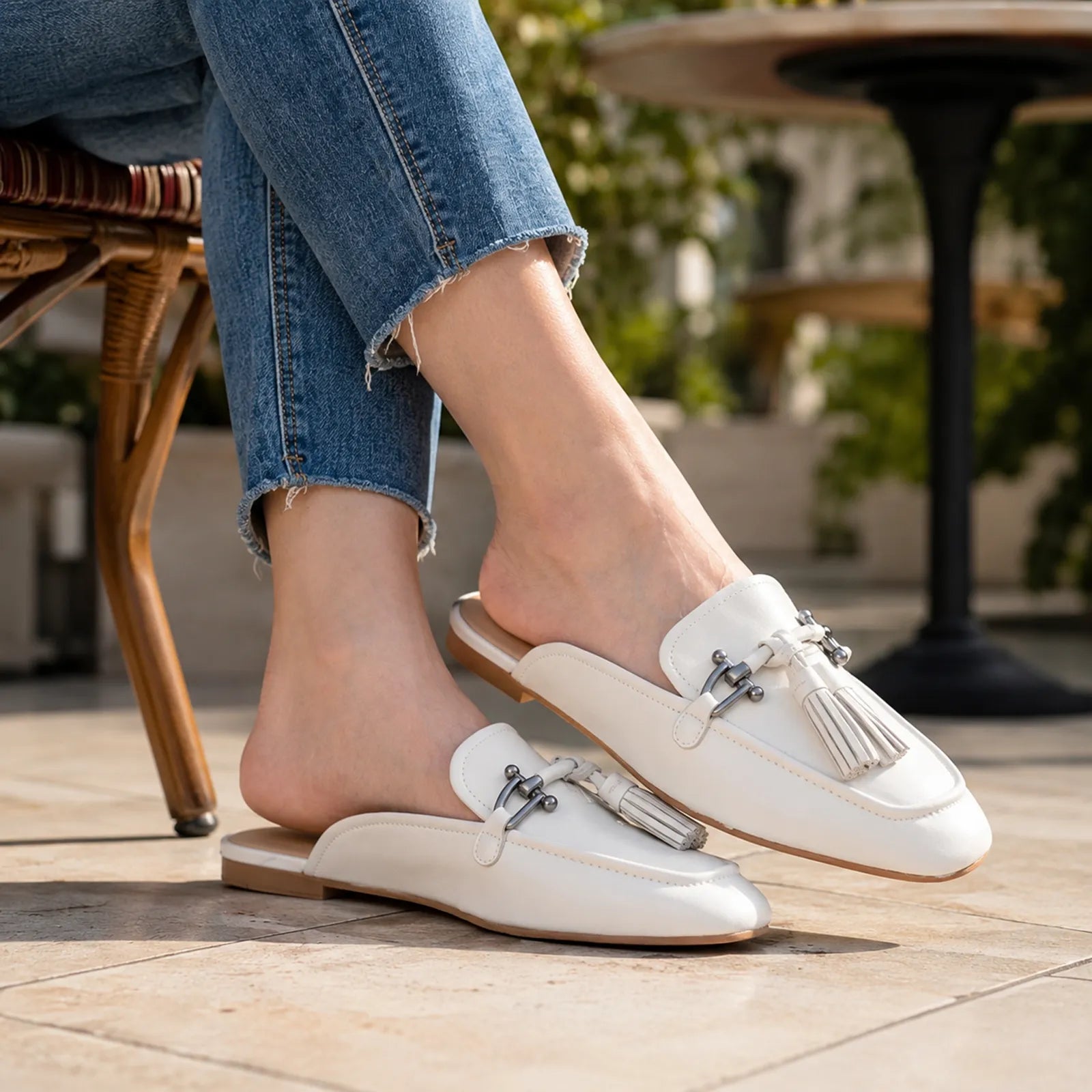 White slip-on flats with tassel hardware trim and low rubber sole