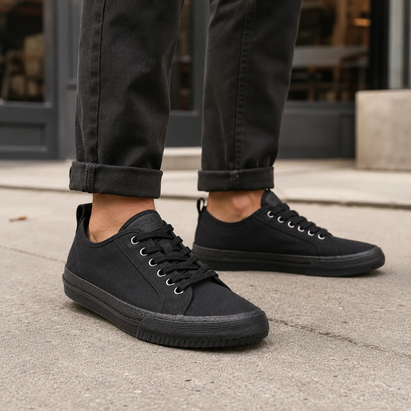 Black low-top lace-up sneakers with metal eyelets and rubber sole