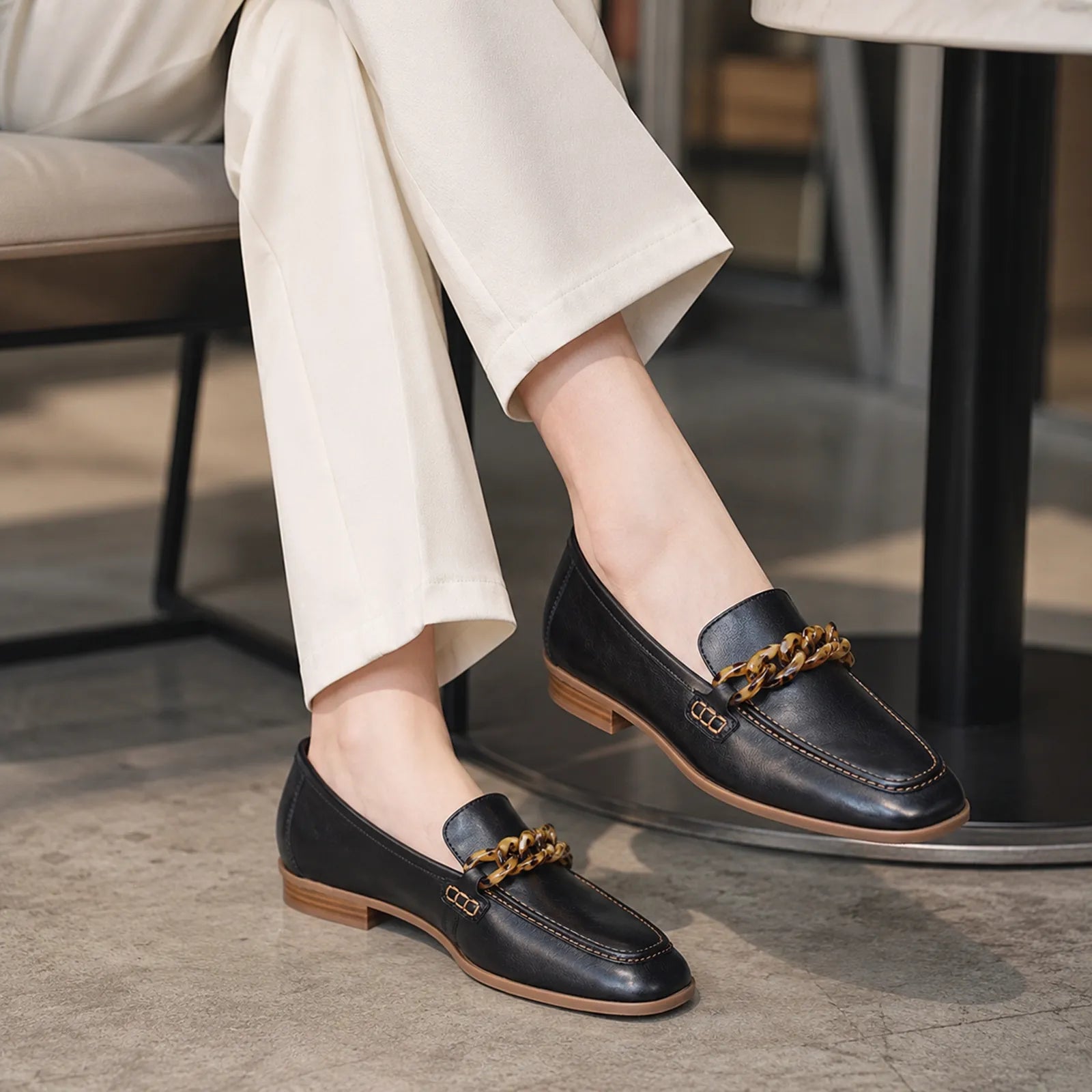 Women's black leather loafer detail view with braided chain bit and stitched trim