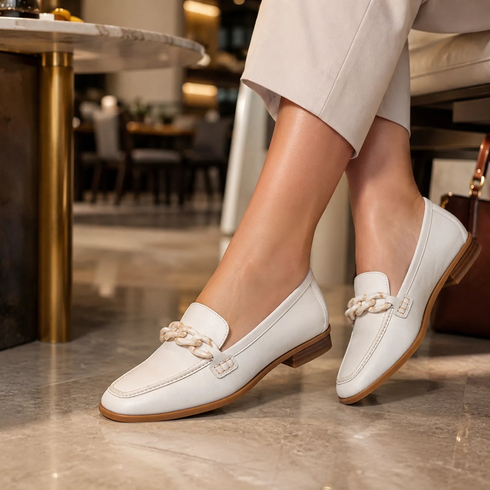 White leather loafers with braided chain detail and low block heel, side view.
