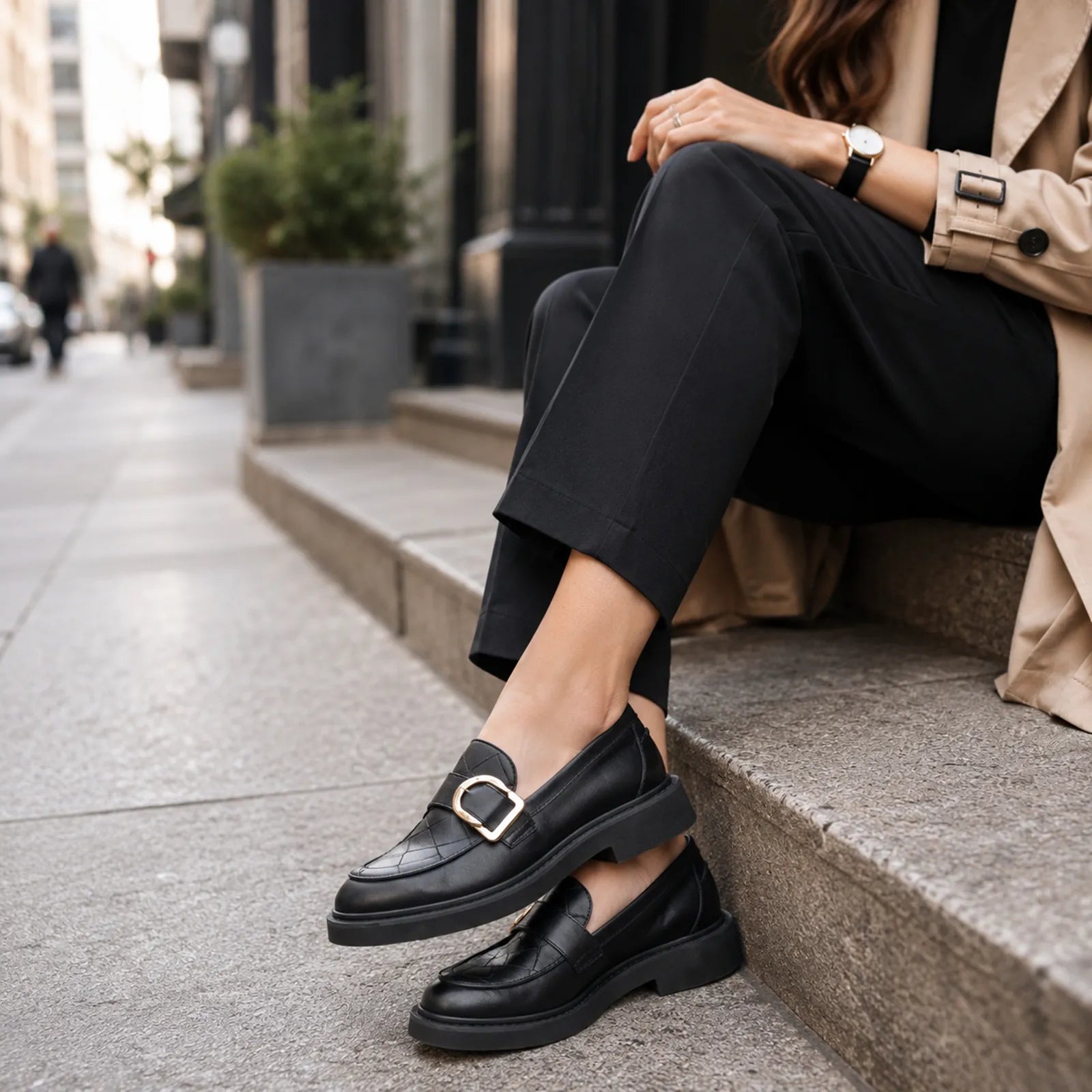 Black penny loafers with metal buckle worn with dark pants and cuffed hem