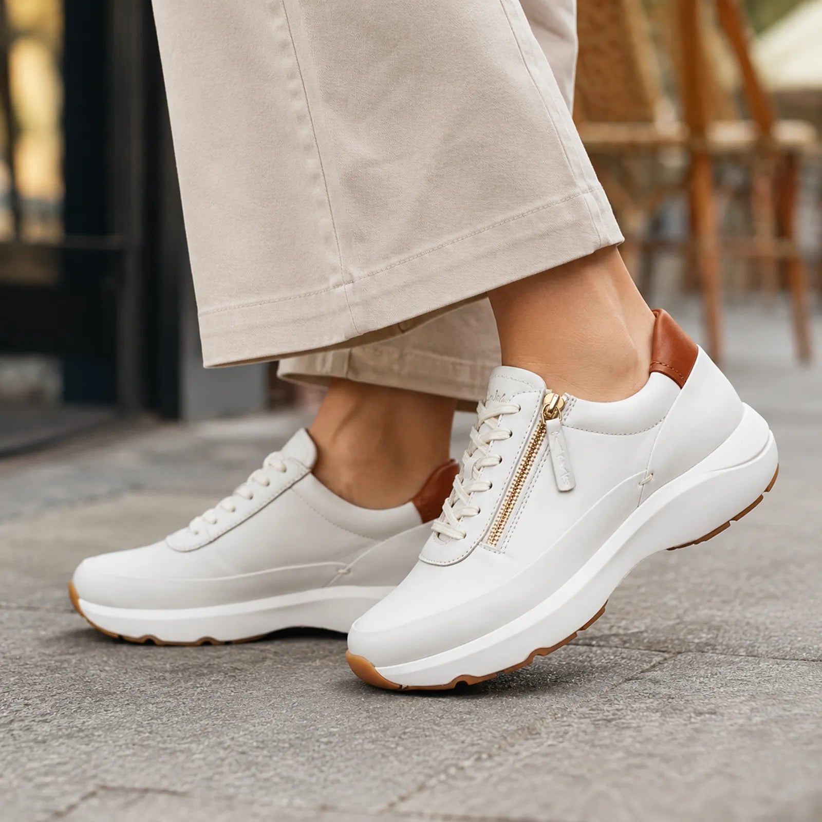 Beige leather womens sneakers with side zip, worn with cropped pants