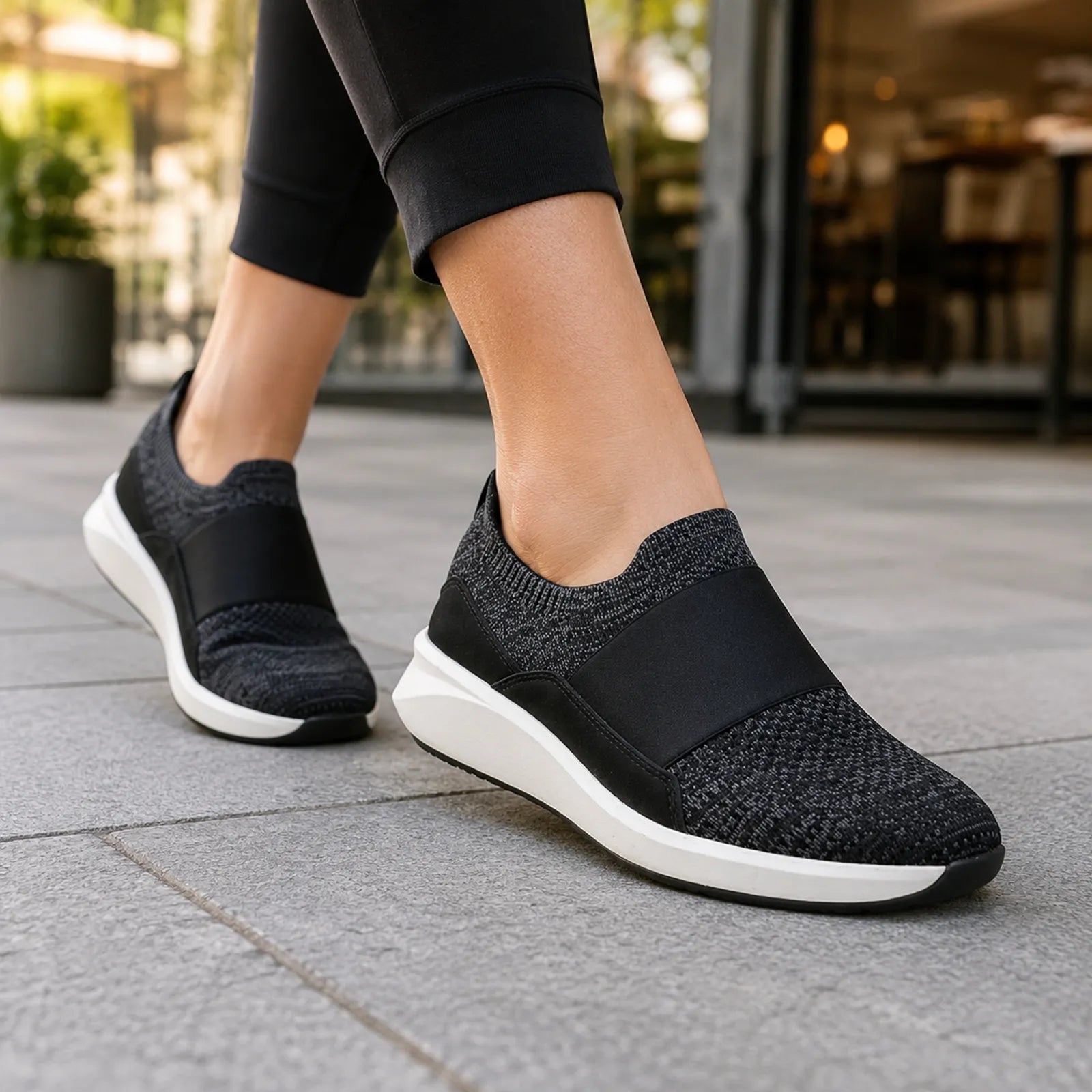 Black knit slip-on sneaker with elastic gore and cushioned white sole, side view.