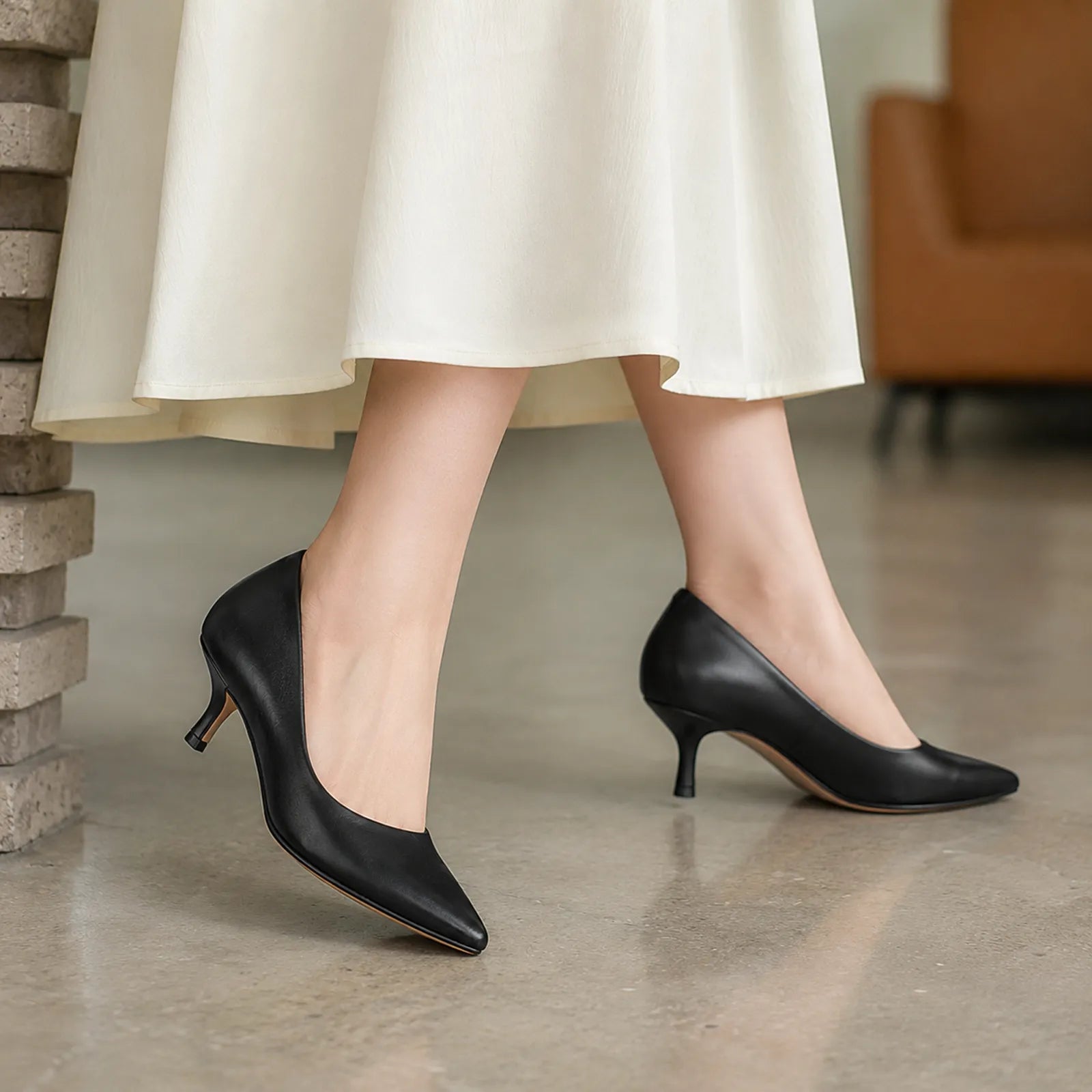 Women's black pointed-toe slip-on heels on model, with slim stiletto heel