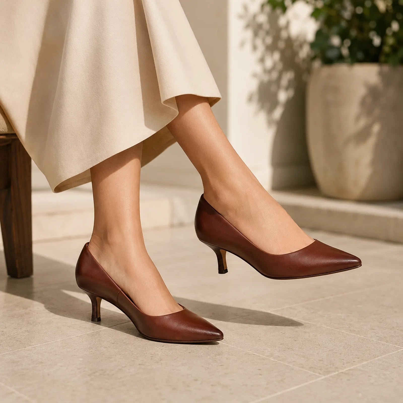 Women's brown pointed-toe slip-on stiletto heels on model with smooth leather finish