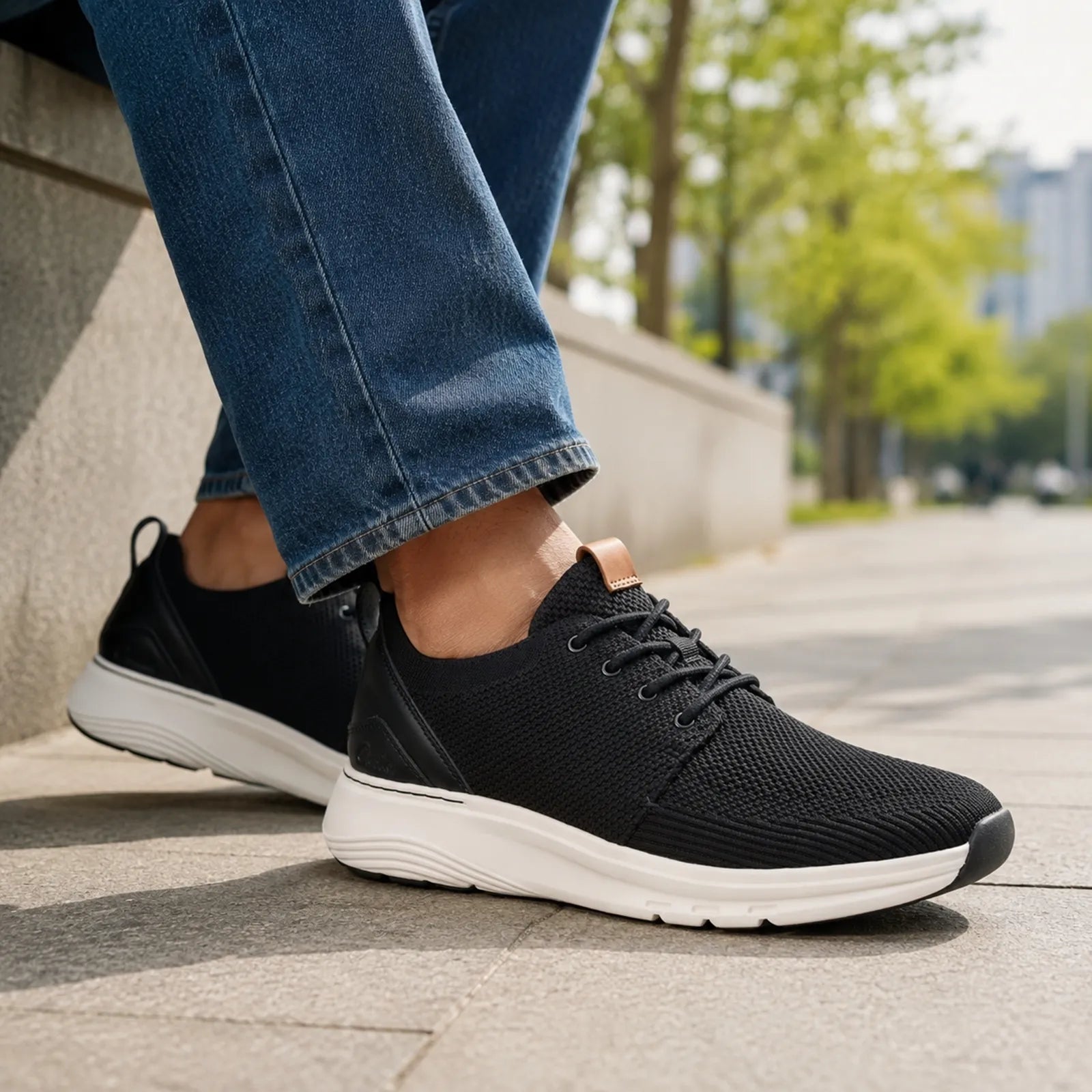 Men's black lace-up walking sneakers worn with jeans; white midsole and tan heel detail