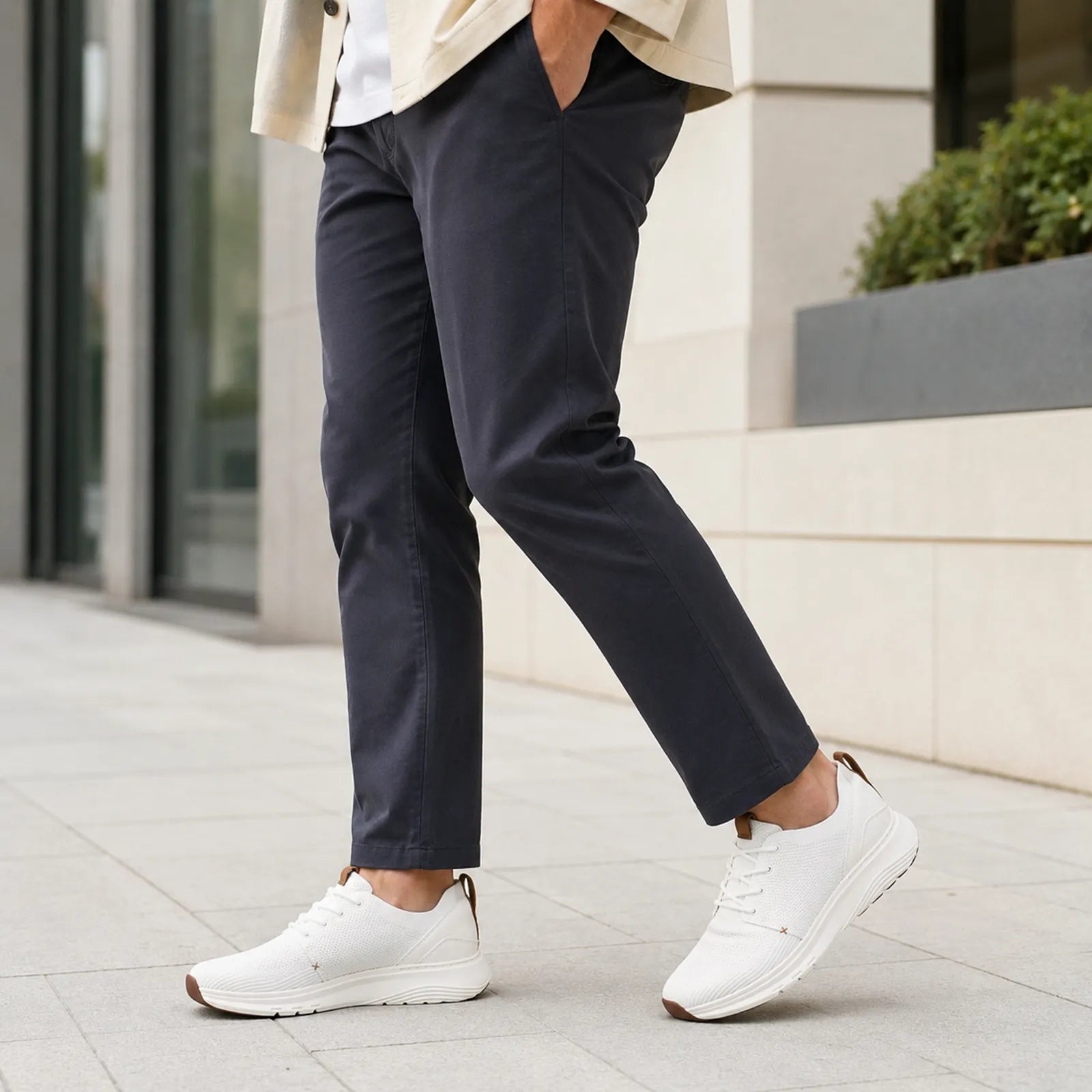 Men's white knit lace-up sneakers on pavement with brown heel tab and low profile sole
