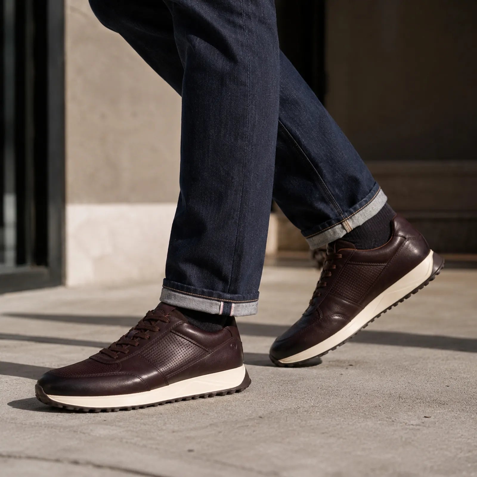 Brown leather lace-up sneakers worn with white outsole and dark textured uppers