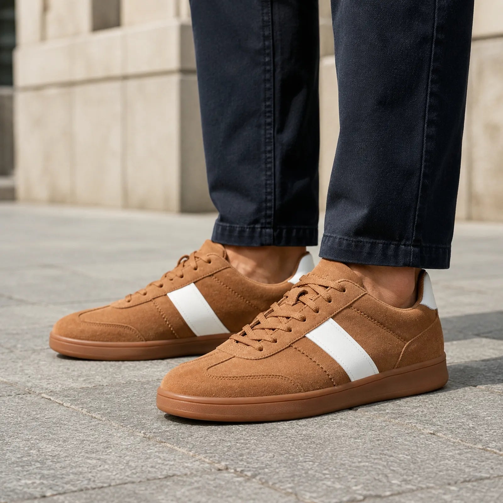 Men's brown suede lace-up sneakers with white side stripe, on pavement
