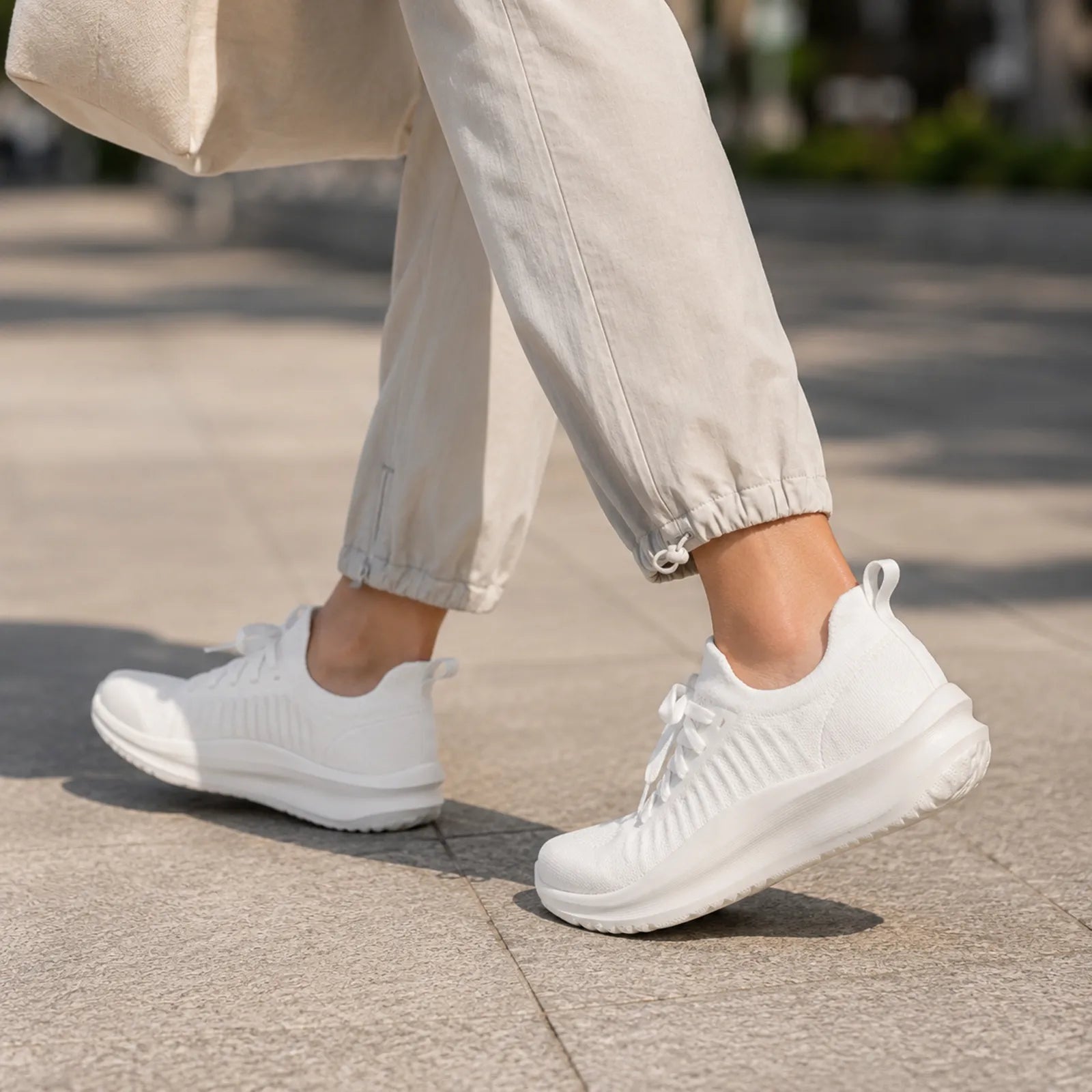 White knit lace-up sneakers on pavement with low-profile cushioned sole