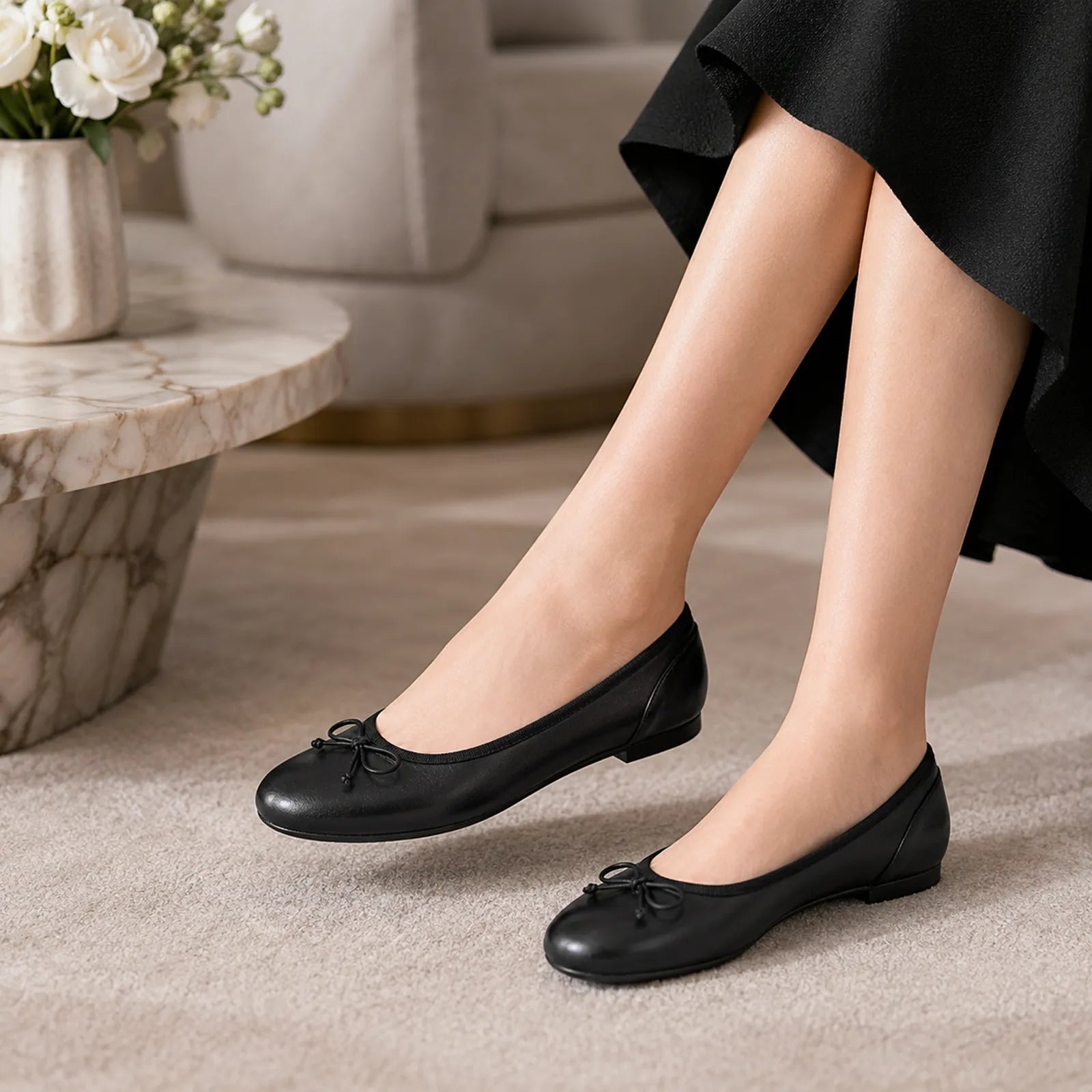 Black leather ballet flats with bow tie, low heel, close-up on legs