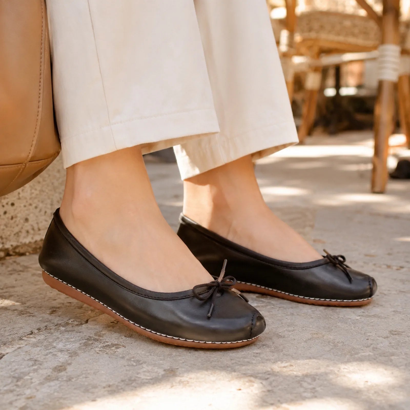 Dark leather flats with tied bow and contrast-stitched trim, low rubber sole