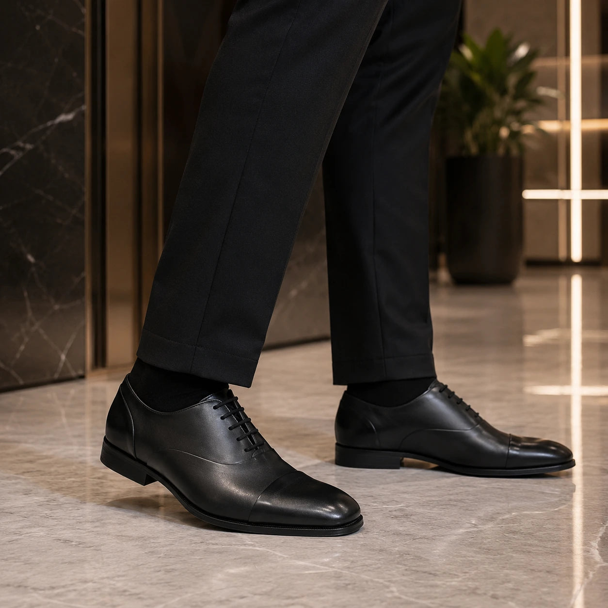 Men's black leather lace-up business shoes with suit trousers on polished floor
