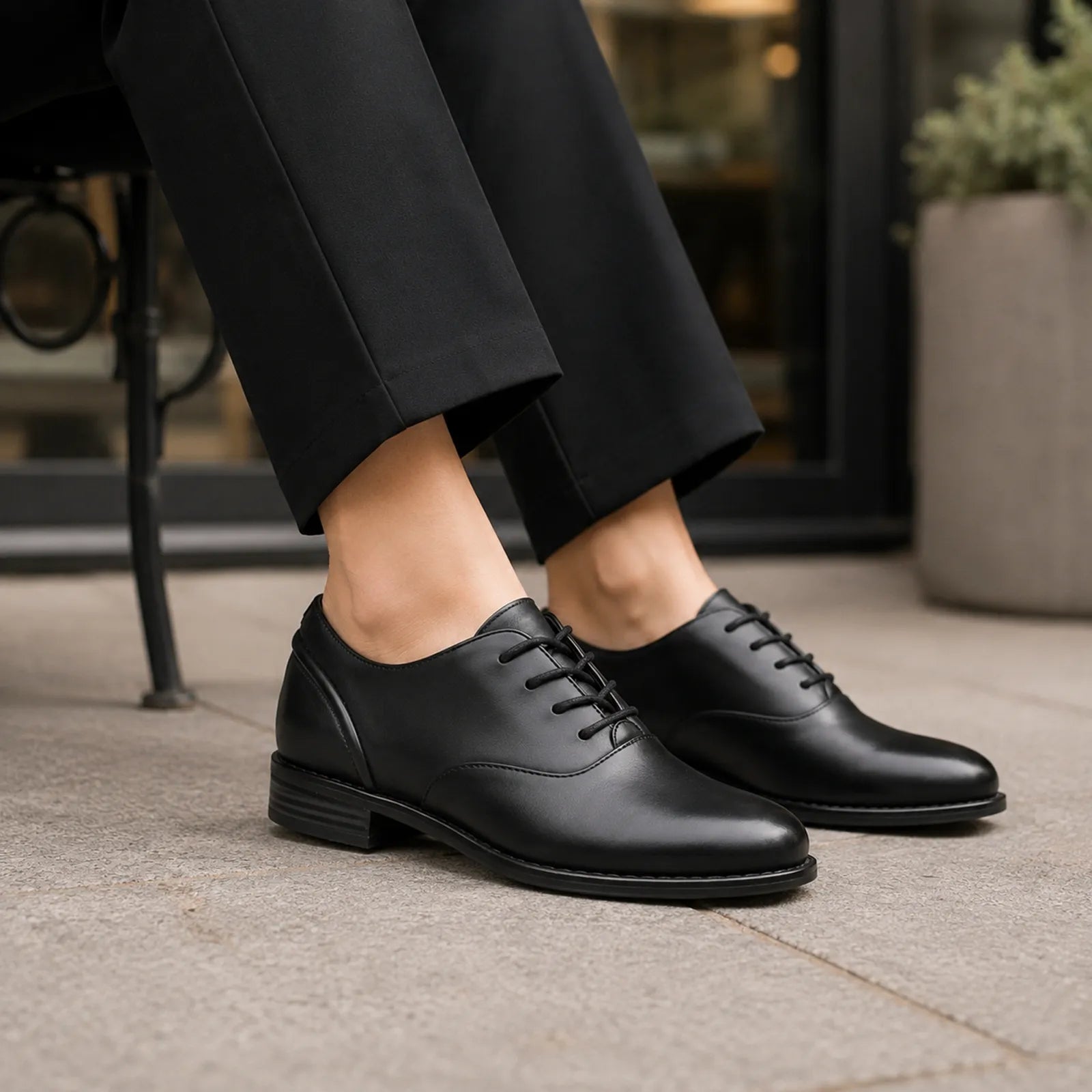 Black leather lace-up oxford shoes with dark trousers hem, close-up